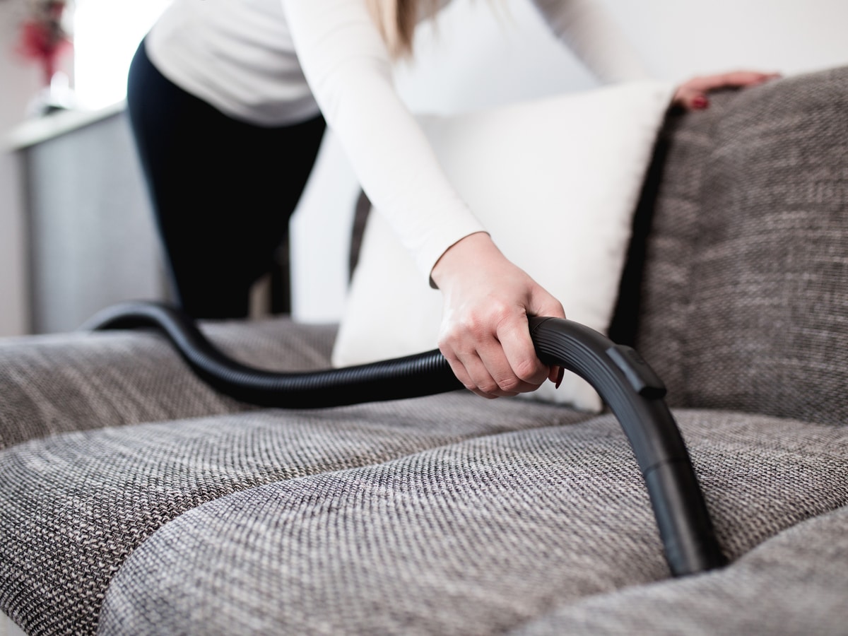 Woman-leaning-over-couch-to-vacuum-between-cushions.jpg